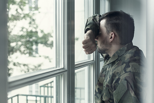 Soldier Leaning on Glass Door of Tampa Clinic Before Scheduled Depression Treatment